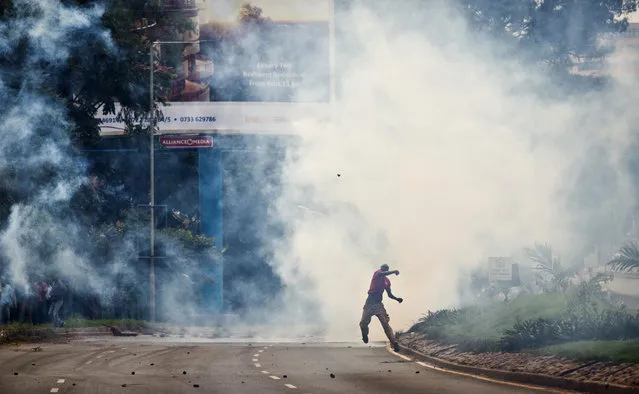 An opposition supporter standing amidst clouds of tear gas throws a rock towards riot police, during a protest in downtown Nairobi, Kenya Monday, May 9, 2016. Kenyan police have tear-gassed opposition supporters after some pelted police with rocks during a protest demanding the disbandment of the electoral authority over alleged bias and corruption. (Photo by Ben Curtis/AP Photo)