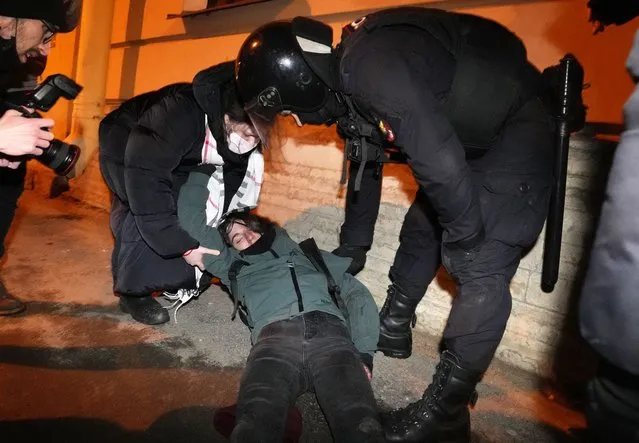 A policeman looks at a young demonstrator who lost consciousness while being detained at an action against Russia's attack on Ukraine in St. Petersburg, Russia, Monday, February 28, 2022. Protests against the Russian invasion of Ukraine resumed on Monday, with people taking to the streets of Moscow and St. Petersburg and other Russian towns despite mass arrests. (Photo by Dmitri Lovetsky/AP Photo)