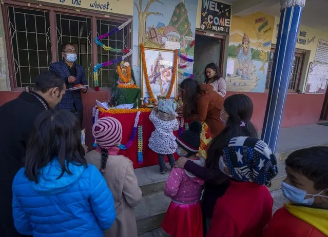 Nepalese students offer prayers before a picture of Hindu goddess Saraswati at a school during Shri Panchami festival in Kathmandu, Nepal, Sunday, February 6, 2022. Saraswati, the goddess of knowledge and learning is worshipped during this festival.Young children are also given their first reading and writing lesson on this day. (Photo by Niranjan Shrestha/AP Photo)