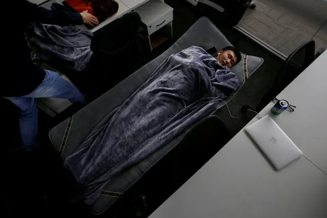 Han Liqun (C), a HR manager of RenRen Credit Management Co., sleeps on a camp bed at the office after finishing work early morning, in Beijing, China, April 27, 2016. (Photo by Jason Lee/Reuters)