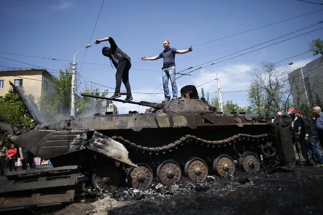 People stand on top of burnt-out armoured personal carrier near the city hall in Mariupol, eastern Ukraine May 10, 2014. At least seven people were killed and dozens wounded in clashes in the port city on Friday, two days before a referendum on self-rule that threatens to plunge the country into civil war. (Photo by Marko Djurica/Reuters)