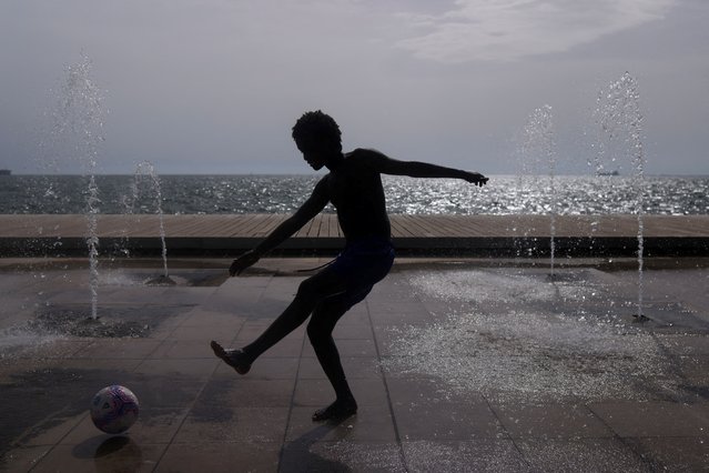 A boy plays with a ball on a fountain, as a heatwave hits Thessaloniki, Greece on June 12, 2024. (Photo by Alexandros Avramidis/Reuters)