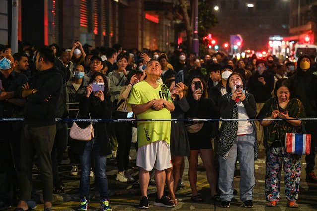 People watch as a fire burns at a high-rise building under construction in the Tsim Sha Tsui district in Hong Kong on March 3, 2023. (Photo by Peter Parks/AFP Photo)