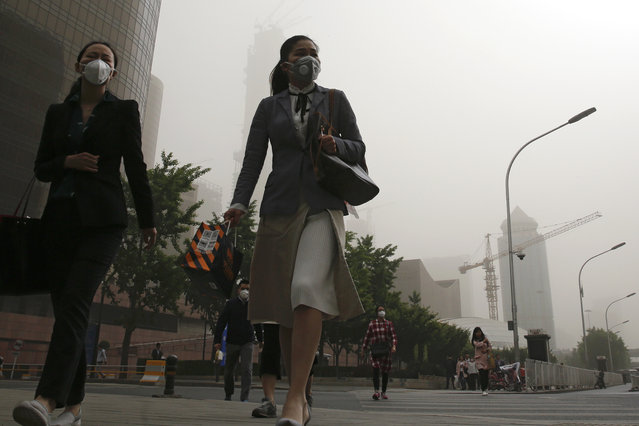 Office workers wearing face masks walk on a street as Beijing is hit by polluted air and sandstorm Thursday, May 4, 2017. Authorities in Beijing issued a blue alert on air pollution as sandstorm swept through the Chinese capital city on Thursday morning. (Photo by Andy Wong/AP Photo)