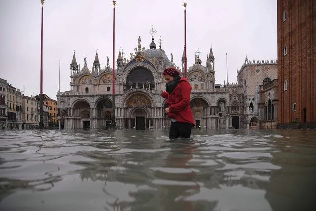 A woman crosses the flooded St. Mark's squareby St. Mark's Basilica after an exceptional overnight “Alta Acqua” high tide water level, early on November 13, 2019 in Venice. Powerful rainstorms hit Italy on November 12, with the worst affected areas in the south and Venice, where there was widespread flooding. Within a cyclone that threatens the country, exceptional high water were rising in Venice, with the sirocco winds blowing northwards from the Adriatic sea against the lagoon’s outlets and preventing the water from flowing back into the sea. At 22:40pm the tide reached 183 cm, the second measure in history after the 198 cm of the 1966 flood. (Photo by Marco Bertorello/AFP Photo)