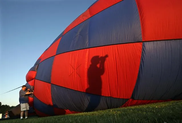 A photographer's shadow is cast on a hot air balloon as it is inflated by a crew during the 33rd annual QuickChek New Jersey Festival of Ballooning at Solberg Airport Friday, July 24, 2015, in Readington, N.J. (Photo by Mel Evans/AP Photo)