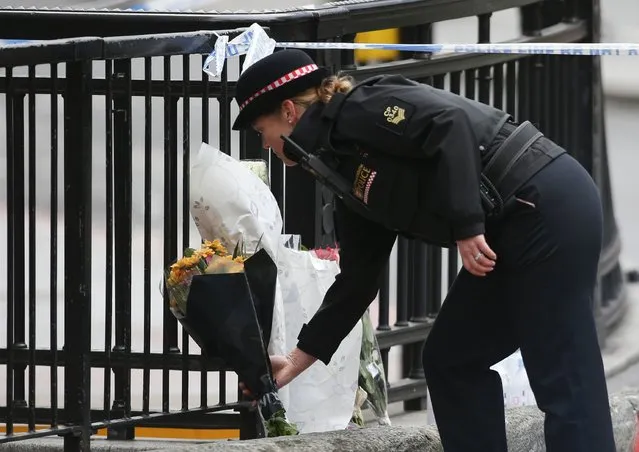 A police officer prepares to lay flowers near London Bridge in London on June 4, 2017, in tribute to the vicitiom of the June 3 terror attack. London Bridge in London on June 4, 2017, as police continue their investigations following the June 3 terror attack. (Photo by Daniel Leal-Olivas/AFP Photo)