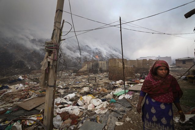 A ragpicker woman living on the edge of Bhalswa landfill walks past during a fire in New Delhi, India, Wednesday, April 27, 2022. (Photo by Manish Swarup/AP Photo)