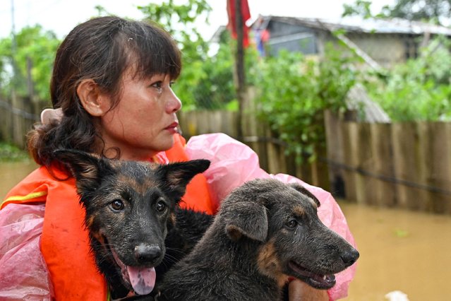 Local resident Phan Thi Tuyet, 50, carries her dogs as she is evacuated on a boat through a flooded street in Hanoi on September 10, 2024, a few days after Typhoon Yagi swept through northern Vietnam. Emergency workers raced to evacuate thousands of people from severe floods after Typhoon Yagi swept through northern Vietnam, killing 63 people and leaving 40 others missing. (Photo by Nhac Nguyen/AFP Photo)