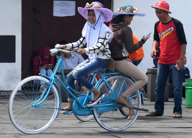 A youth ferries a friend on a rented bicycle on the main square of Jakarta' s old town on April 9, 2017. (Photo by Goh Chai Hin/AFP Photo)