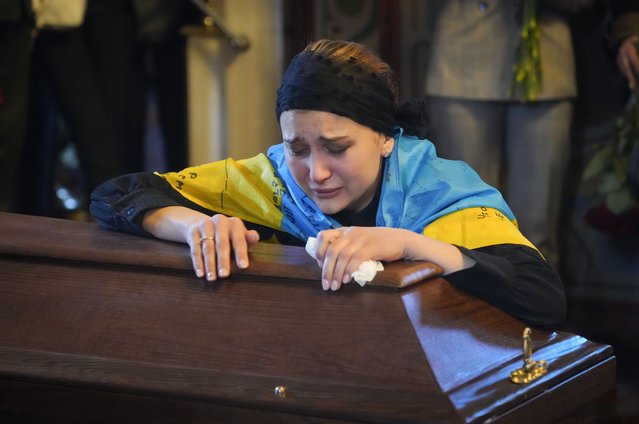 The widow cries at the coffin of volunteer soldier Oleksandr Makhov, 36 a well-known Ukrainian journalist, killed by the Russian troops, at St Michael cathedral in Kyiv, Ukraine, Monday, May 9, 2022. (Photo by Efrem Lukatsky/AP Photo)
