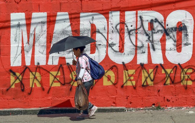 A woman walks in front of a crossed-out advertisment of Venezuelan President Nicolas Maduro in Valencia, state of Carabobo, Venezuela on July 30, 2024. Venezuelan President Nicolas Maduro, whose reelection to a third term has been questioned at home and abroad, accused the opposition Tuesday of “criminal violence” after protests claimed at least four lives (Photo by Juan Carlos Hernández/AFP Photo)