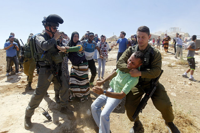 Israeli soldiers clash with Palestinian's during the demolishing of Palestinian houses near the village of Yatta, south of the West Bank city of Hebron, 19 June 2016. One house owner was arrested while the other Palestinians were allowed to leave the site. Four houses were reportedly constructed without permission and located in area C, a closed military zone where Israel exercises full control. (Photo by Abed Al Hashlamoun/EPA)