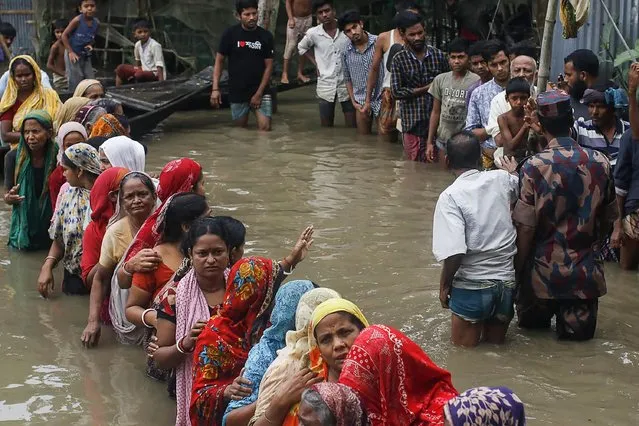 Flood affected people queue in knee-deep flood waters to collect food relief following heavy monsoon rainfalls in Sunamganj on June 21, 2022. At least 26 more people have died in monsoon flooding and lightning strikes in India, as millions remained marooned in the country and neighbouring Bangladesh, authorities said on June 20. (Photo by Md Abu Sufian Jewel/AFP Photo)