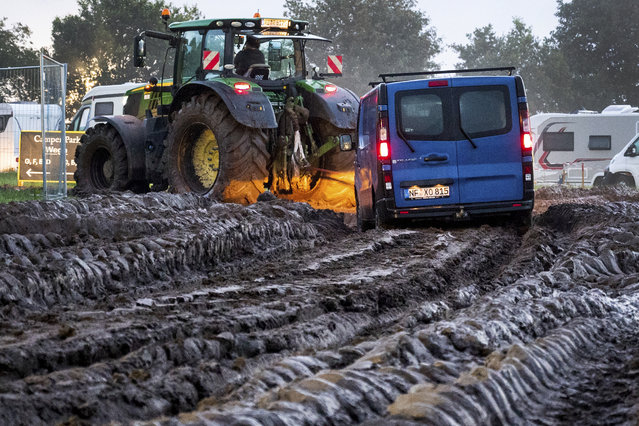 A vehicle is pulled through the mud with the help of a tractor onto the grounds of the heavy metal festival in Wacken, Germany, Wednesday, August 2, 2023. The Wacken Open Air metal festival in northern Germany is opening with a reduced audience after persistent rain turned the grounds to mud and forced organizers to order a halt to all new arrivals. Organizers of the famed music festival, in a rural area northwest of Hamburg, had already told fans on Tuesday that no more cars and trucks could be admitted to the site. (Photo by Daniel Bockwoldt/dpa via AP Photo)