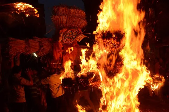 Nepalese men burn a straw effigy of Ghanta Karna during celebrations of the Hindu festival of “Gathemangal”, also known as Ghanta Karna, in Bhaktapur on the outskirts of Kathmandu on July 25, 2014. The Nepalese festival, which celebrates the defeat of the mythical demon Ghanta Karna (“bell-ears”), is celebrated by performing the legendary drama in the streets. (Photo by Prakash Mathema/AFP Photo)