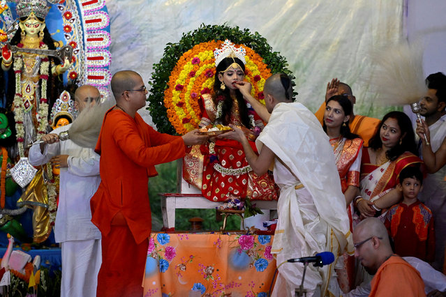 Hindu priests offer sweets to a young girl dressed as “Kumari” who is worshipped during the Durga Puja festival, at a temple in Dhaka, Bangladesh, on October 11, 2024. (Photo by Fatima Tuj Johora/Reuters)