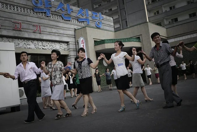 North Koreans gather for a dance in downtown Pyongyang, Sunday, July 27, 2014 in North Korea. North Korea celebrated its 61st anniversary of the armistice that ended the Korean War Sunday, and took the opportunity to spend their Sunday off, a national holiday, with family and friends. (Photo by Wong Maye-E/AP Photo)