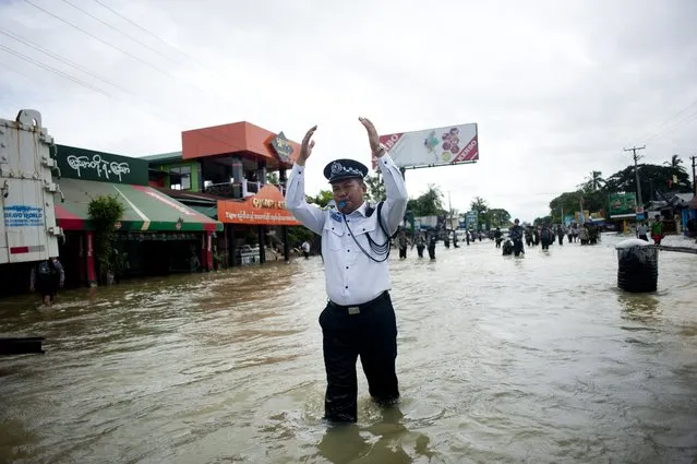 A traffic police officer directs traffic on a flooded street in Bago township, around 100 kilometres (62miles) north of Yangon on August 8, 2014. Heavy downpours in recent days have caused severe flooding in Bago and Mon states. (Photo by Ye Aung Thu/AFP Photo)