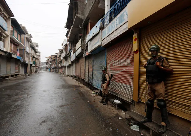 Indian policemen stand guard in front of closed shops during a curfew in Srinagar, July 10, 2016. (Photo by Danish Ismail/Reuters)