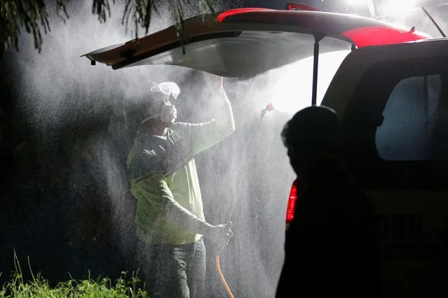 A municipal worker sprays with disinfectant, an ambulance carrying the coffin of a coronavirus disease (COVID-19) victim, in Jakarta, Indonesia, March 31, 2020. (Photo by Willy Kurniawan/Reuters)