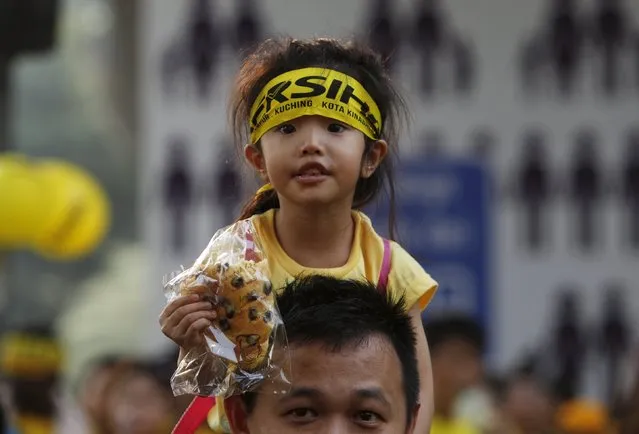 A supporter of pro-democracy group “Bersih” (Clean) carries a child on his shoulders outside Dataran Merdeka in Malaysia's capital city of Kuala Lumpur August 30, 2015. Thousands gathered for a second day of protests on Sunday to demand the resignation of Prime Minister Najib Razak over a multi-million-dollar financial scandal, their spirits lifted by unexpected support from Malaysia's longest-serving leader. (Photo by Edgar Su/Reuters)