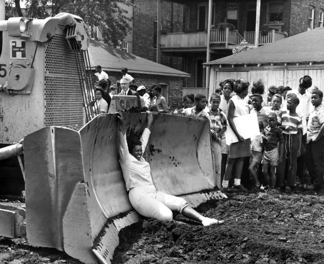 A woman hangs on blade of a bulldozer, which was parked at construction site of mobile classroom units at 74th Street and Lowe Ave in Chicago's South Side, August 2, 1963. Demonstration was staged by CORE which contends that black pupils should be sent to existing predominantly white schools rather than in temporary classrooms. (Photo by AP Photo)
