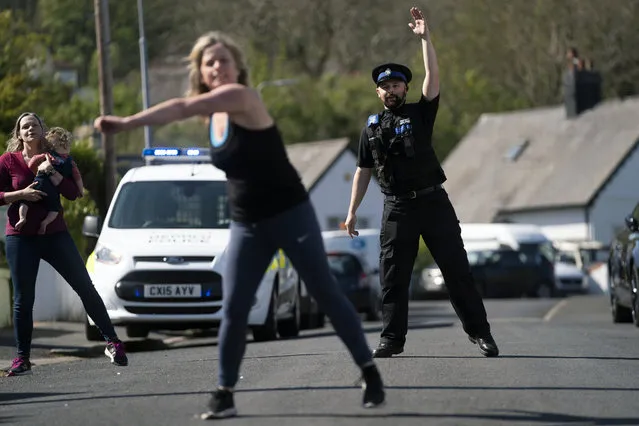 PCSO Steve Gunning takes part in a dance session, organized by residents of a suburban street in north Wales to help them keep fit, socialize and deal with the effects of COVID-19 during the coronavirus outbreak Prestatyn in north Wales, Tuesday April 21, 2020. (Photo by AP Photo/Stringer)