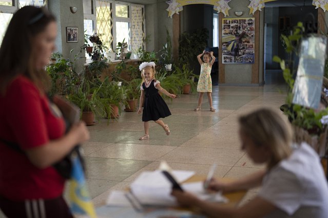 Girls play as a woman distributes iodine tablets to residents at a local school in case of a radiation leak in Zaporizhzhia, Ukraine, Friday, September 2, 2022. Heavy fighting continued Friday near Europe's largest nuclear power plant in a Russian-controlled area of eastern Ukraine, a day after experts from the U.N.'s nuclear watchdog agency voiced concerns about structural damage to the sprawling Zaporizhzhia site. (Photo by Leo Correa/AP Photo)