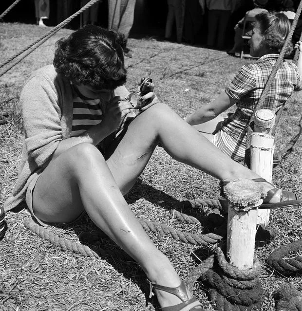 A circus girl sitting on the ground and applying cream on a wound during a rehearsal for the Ringling Bros. and Barnum & Bailey Circus in Sarasota, FL in 1949. (Photo By Nina Leen/Time Life Pictures/Getty Images)