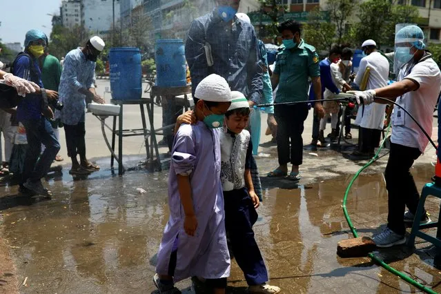 A man sprays disinfectants as children enters the Baitul Mokarram National Mosque to attend Friday Prayer after the government has eased the restrictions amid concerns over the coronavirus disease (COVID-19) outbreak in Dhaka, Bangladesh, May 8, 2020. (Photo by Mohammad Ponir Hossain/Reuters)