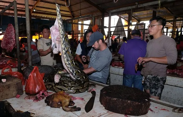 This photo taken on February 8, 2020 shows a vendor slicing up a large snake at the Tomohon Extreme Meat market on Sulawesi island, as business is booming and curious tourists keep arriving to check out exotic fare that enrages animal rights activists. link. Bats, rats and snakes are still being sold at an Indonesian market known for its “extreme” wildlife offerings, despite calls to take them off the menu over fears of COVID-19 coronavirus link. (Photo by Ronny Adolof Buol/AFP Photo)