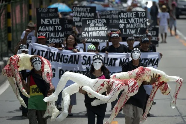 Activists hold mock dead bodies during a protest marking the 42nd declaration of Martial Law at the Armed Forces of the Philippines (AFP) headquarters in Manila on September 21, 2014. The protest aims to honor and seek justice for those that died during martial law. (Photo by Noel Celis/AFP Photo)