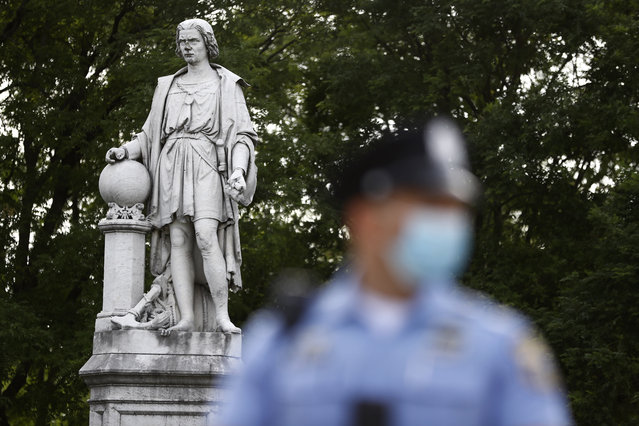 A Philadelphia police officer stands near the statue of Christopher Columbus at Marconi Plaza, Monday, June 15, 2020, in the South Philadelphia neighborhood of Philadelphia. (Photo by Matt Slocum/AP Photo)