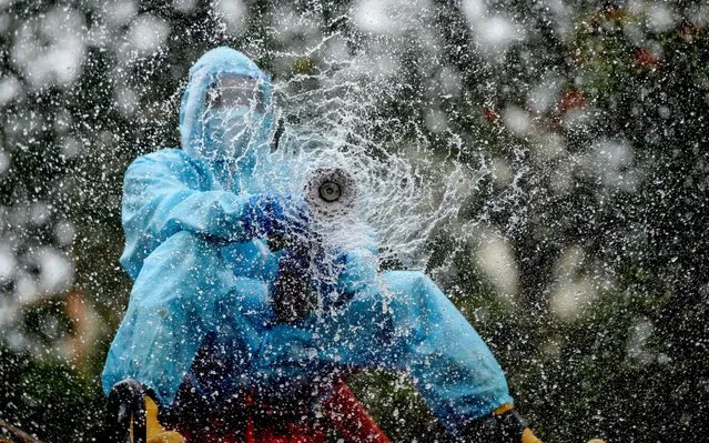 A firefighter sprays disinfectant as a preventive measure against the spread of the COVID-19 coronavirus in a containment zone in Chennai on May 11, 2020. (Photo by Arun Sankar/AFP Photo)