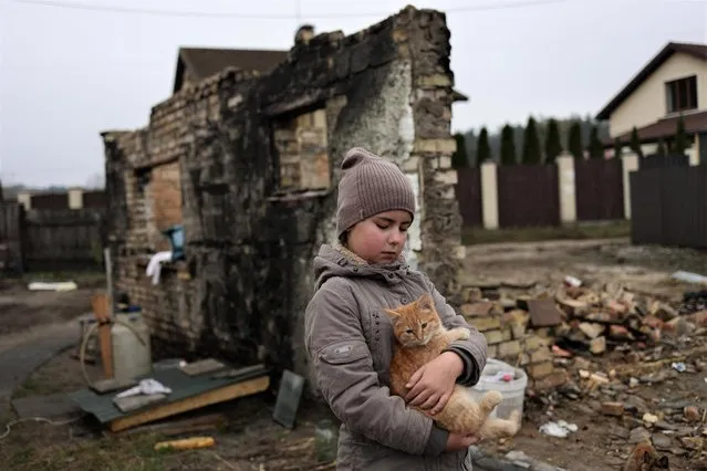 Yuliia Zaika, a 9-year old Ukrainian girl, holds her cat Marsyk outside her half-sister Kateryna Tyshchenko's destroyed house in the village of Moshchun near Kyiv, Ukraine on November 8, 2022. (Photo by Murad Sezer/Reuters)