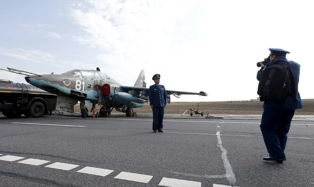 A Chinese military officer poses for a picture near the Belarussian Sukhoi Su-25 military jet during military exercises near the village of Krysovo, southwest of Minsk, September 23, 2015. (Photo by Vasily Fedosenko/Reuters)