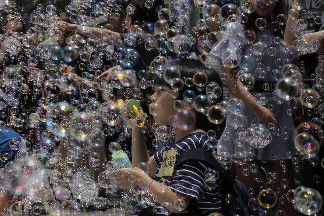 A boy plays with bubbles during an art display titled “Bubble Up” created by Japanese artist Shinji Ohmaki in Hong Kong, Wednesday, August 2, 2017. (Photo by Kin Cheung/AP Photo)