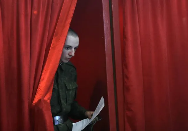 A Belarusian soldier leaves a voting booth at a polling station during early voting in Minsk, Belarus, Tuesday, September 6, 2016. The early voting is conducted five days before parliamentary elections on Sunday, Sept. 11. (Photo by Sergei Grits/AP Photo)