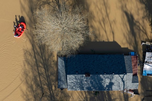 People ride an inflatable boat in front of a flooded home in Frankfort, Kentucky, on Monday, April 7, 2025. Floodwaters inundated communities across a broad swath of the central United States on Sunday and Monday, the result of days of rain. (Photo by William DeShazer/The New York Times/Redux)