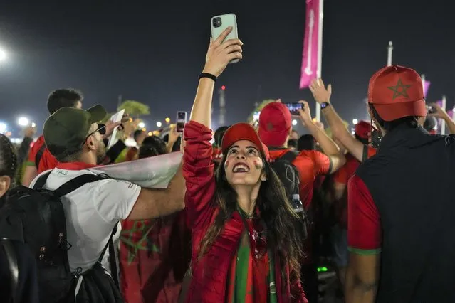 Morocco soccer team fan uses her mobile phone as supporters cheer while they their walk towards Al Bayt Stadium prior of the World Cup semifinals soccer match between France and Morocco in Doha, Qatar, Wednesday, December 14, 2022. (Photo by Frank Augstein/AP Photo)