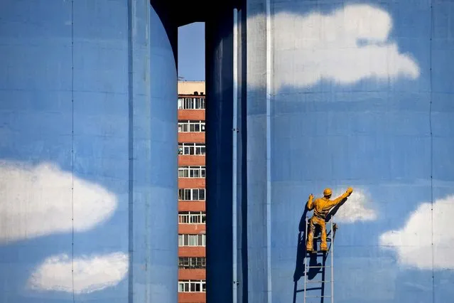 A model of a worker painting blue sky and white clouds is installed on the exterior of a building of a power plant in Beijing, China. (Photo by Alexander F. Yuan/Associated Press)