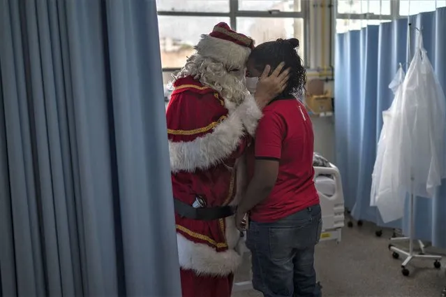 Public worker Ari Queiroz, 59, dressed as Santa Claus, hugs a mother of a patient of the ICU Pediatric ward of the Souza Aguiar Municipal Hospital in Rio de Janeiro, Brazil, on December 22, 2022. Queiroz, who distributes vaccines and medicines for the Health Department of Rio de Janeiro, has been turning into Santa Claus every Christmas and visiting hospitals for the past two decades. (Photo by Mauro Pimentel/AFP Photo)