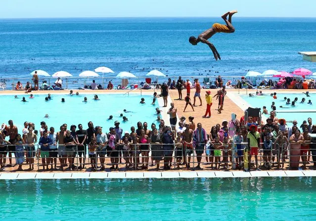 A person dives from a springboard in front of beach-goers during a hot summer day at Sea Point swimming pool in Cape Town, South Africa on December 27, 2022. (Photo by Esa Alexander/Reuters)