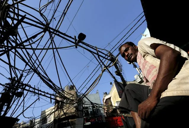 A cycle rickshaw puller waits for passengers under overhead power cables in an alley in the old quarters of Delhi, India, in this September 10, 2015 file photo. India's prime minister is to tell states to raise electricity prices in return for access to a financial bailout package, a politically contentious move that risks a backlash from farmers and consumers long used to free or cheap power. (Photo by Adnan Abidi/Reuters)