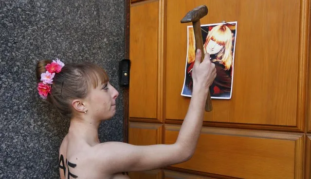An activist from women's rights group Femen nails a photo of her sister to a door as she protests against the kidnapping of her sister, outside the Security Service of Ukraine (SBU) headquarters in Kiev, December 1, 2014. According to the protester, her sister was kidnapped in Ukraine and she was protesting to demand that the SBU steps in to help find her sister. (Photo by Valentyn Ogirenko/Reuters)