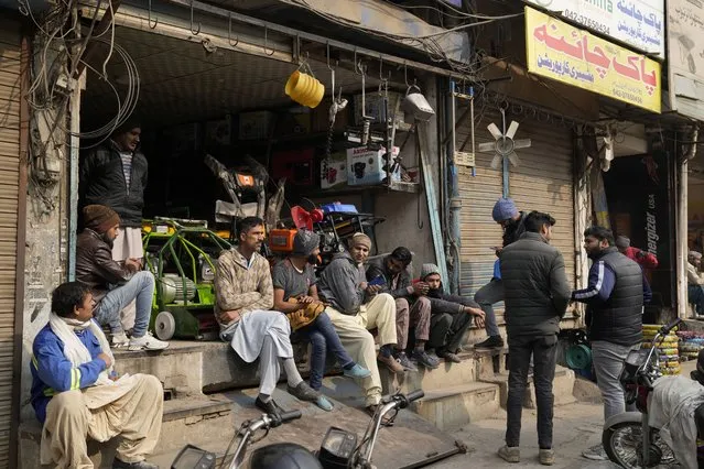 Shopkeepers and workers wait for electric power at a market following a power breakdown across the country, in Lahore, Pakistan, Monday, January 23, 2023. Much of Pakistan was left without power for several hours on Monday morning as an energy-saving measure by the government backfired. The outage spread panic and raised questions about the cash-strapped government’s handling of the crisis. (Photo by K.M. Chaudary/AP Photo)