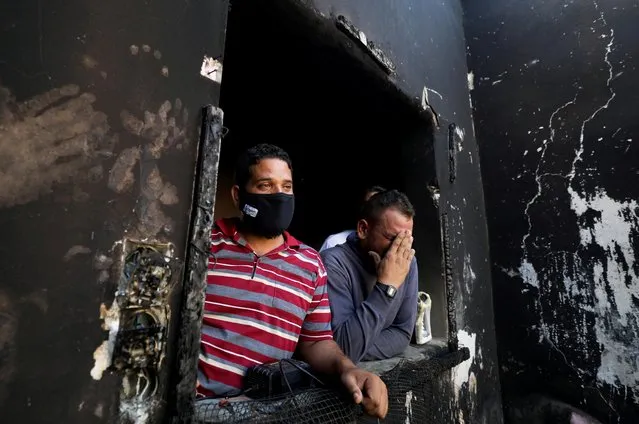Palestinian man Omar Al-Hazeen (R) reacts at his torched house where his three children were killed in a fire ignited by a candle used to light up their room during a power cut in the central Gaza Strip on September 2, 2020. (Photo by Mohammed Salem/Reuters)