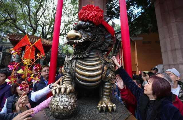 People touch a statue of a lion for good luck as they leave the Wong Tai Sin temple during Lunar New Year celebrations for the Year of the Dog in Hong Kong on February 17, 2018. (Photo by Vivek Prakash/AFP Photo)
