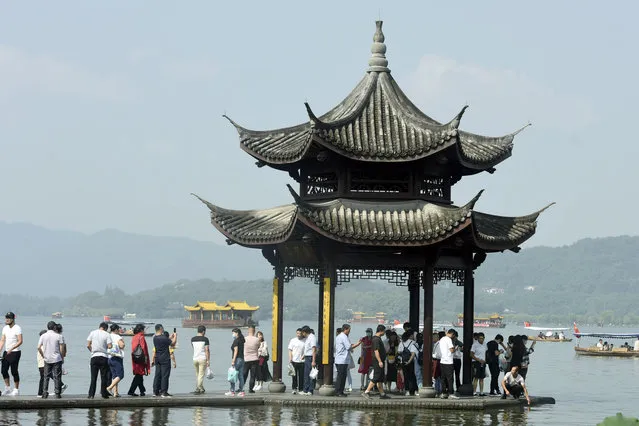Tourists gather at a waterfront pavilion at the West Lake in Hangzhou in eastern China's Zhejiang Province, Thursday, October 1, 2020. Millions of Chinese tourists usually would use their week-long National Day holidays to travel abroad. This year, travel restrictions due to the coronavirus pandemic mean that some 600 million tourists – about 40% of the population – will travel within China during the holiday that began Thursday, according to Ctrip, China's largest online travel agency. (Photo by Chinatopix via AP Photo)